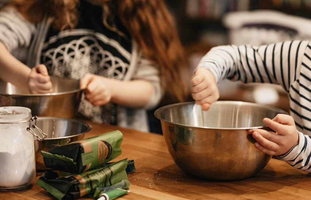 Hands of children stirring in mixing bowls